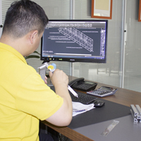 Engineer analyzing a CAD design on a computer screen while holding a part.