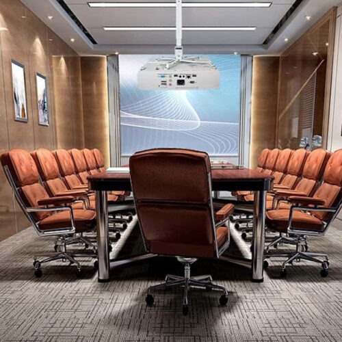 Conference room featuring a ceiling-mounted projector and a large table surrounded by leather chairs.