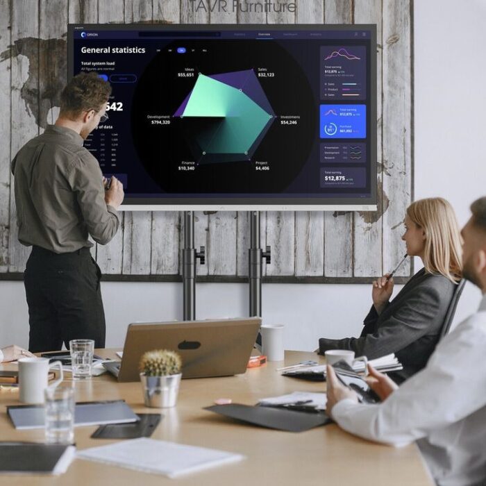 A professional presenting data on a large smart screen in a meeting room.