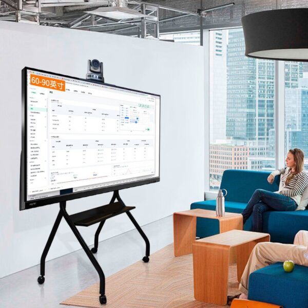 A smart display on a mobile stand with a mounted camera in a modern office lounge.