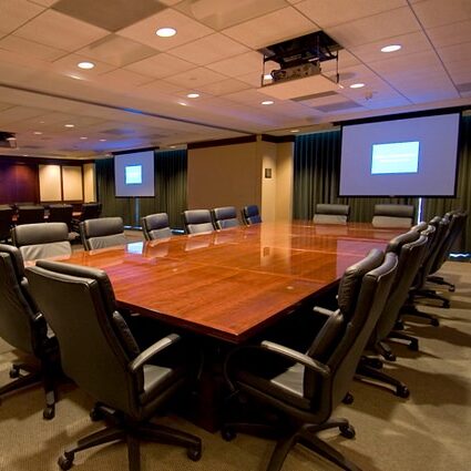 A modern boardroom with a long wooden table and chairs.